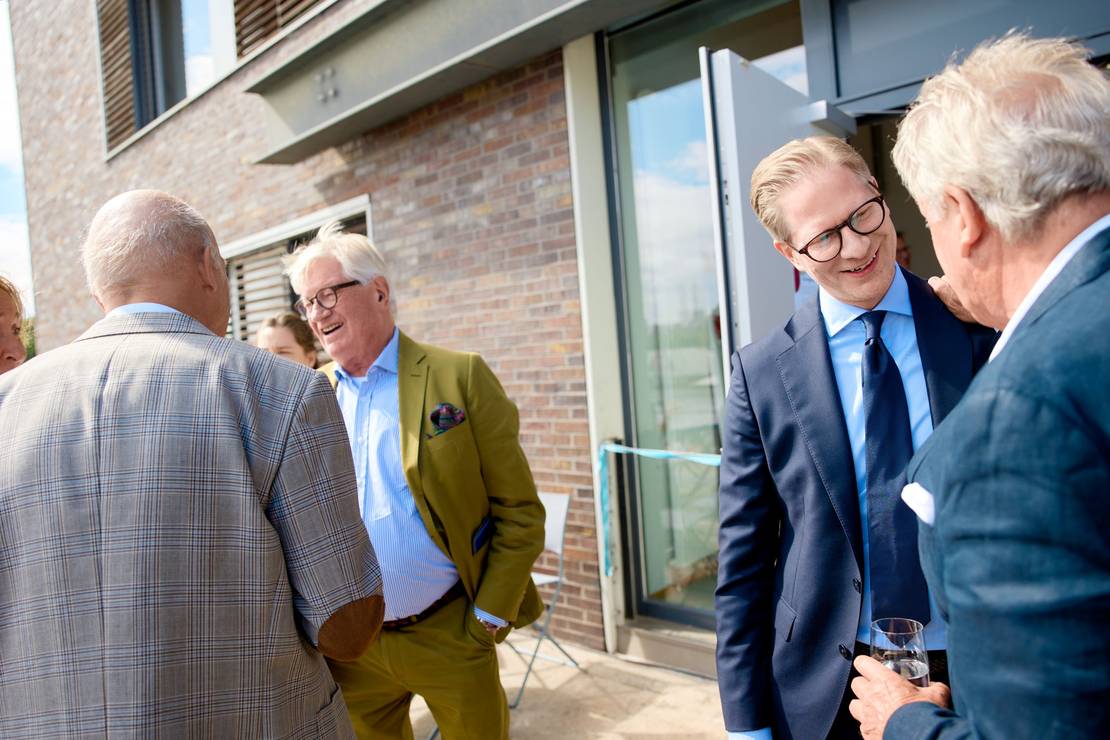 Georg Joachim Claussen und Carl Johann Claussen unterhalten sich mit Gästen.