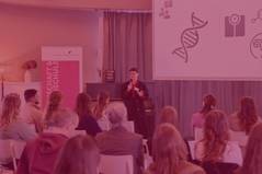 Bild eines vortragenden Stipendiaten vor einem Plenum von Stipendiat:innen, Foto mit rotem Overlay und Beschriftung: Master Plus