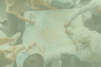 Landkarte von oben fotografiert, umringt von Jugendlichen, auf Orte zeigend, Foto mit grünem Overlay und Beschriftung Zugvogel