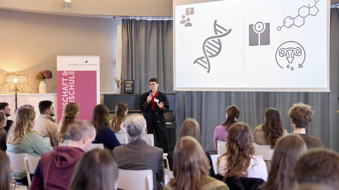 Stipendiatin hält vor Zuschauer:innen einen Vortrag mit Powerpoint