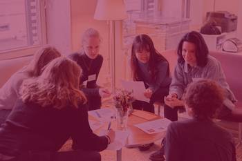 Bild von Stipendiatinnen um einen runden Tisch sitzend im Austausch, Foto mit rotem Overlay und Beschriftung: B-MINT