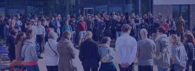 Eine große Gruppe junger Menschen im kreis stehend auf einer Wiese, Foto mit blauem Overlay
