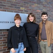 Foto von drei Personen. Zwei Frauen und ein Mann, die in die Kamera lachen.