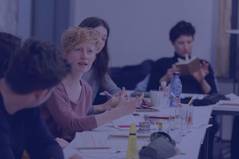 Stipendiat:innen an Tischen sitzend während eines Workshops, Bild mit blauem Overlay