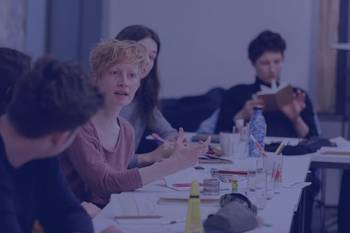 Stipendiat:innen an Tischen sitzend während eines Workshops, Bild mit blauem Overlay