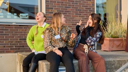 Lachende junge Frauen sitzen auf den Stufen vor der Claussen-Simon-Stiftung