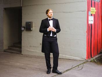 Porträt des Musikers Felix Stachelhaus, stehend im Frack an einem Bühneneingang