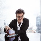 Porträt von Alan Gilbert mit einem kleinen Modell der Elbphilharmonie