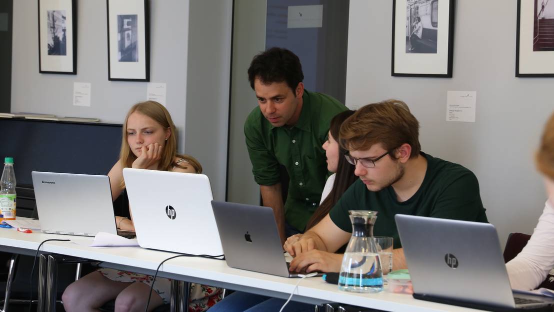 drei Menschen vor einem aufgeklappten Laptop