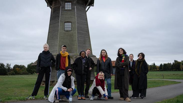 Gruppenfoto von einer Gruppe Leute vor einer alten Mühle.
