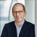 Porträt von Christoph Lieben-Seutter, mit verschränkten Armen im Foyer der Elbphilharmonie stehend